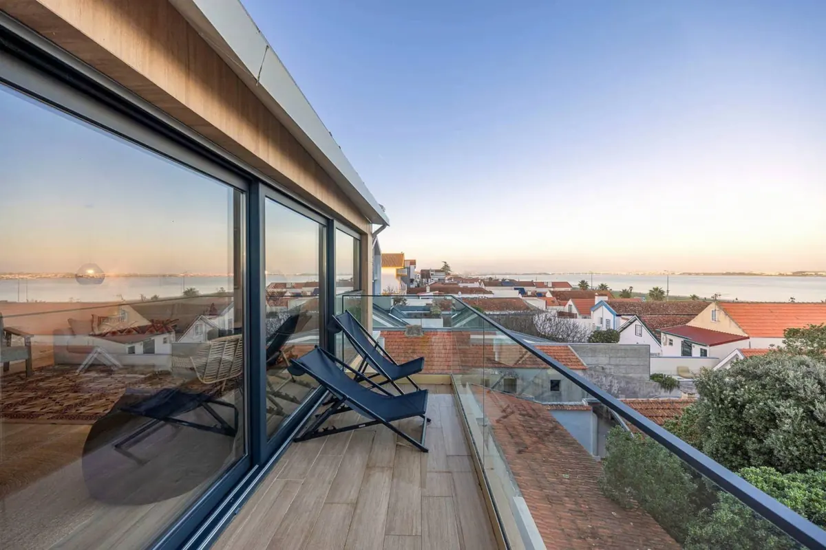 Terraço com espreguiçadeiras ao pôr do sol, sobre os telhados da Costa Nova e a Ria ao fundo