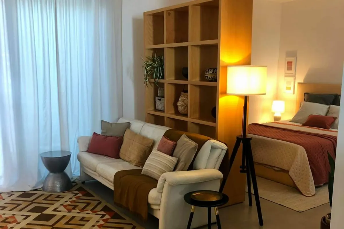 Vista do estúdio em open space, com a zona de estar em primeiro plano e a cama ao fundo