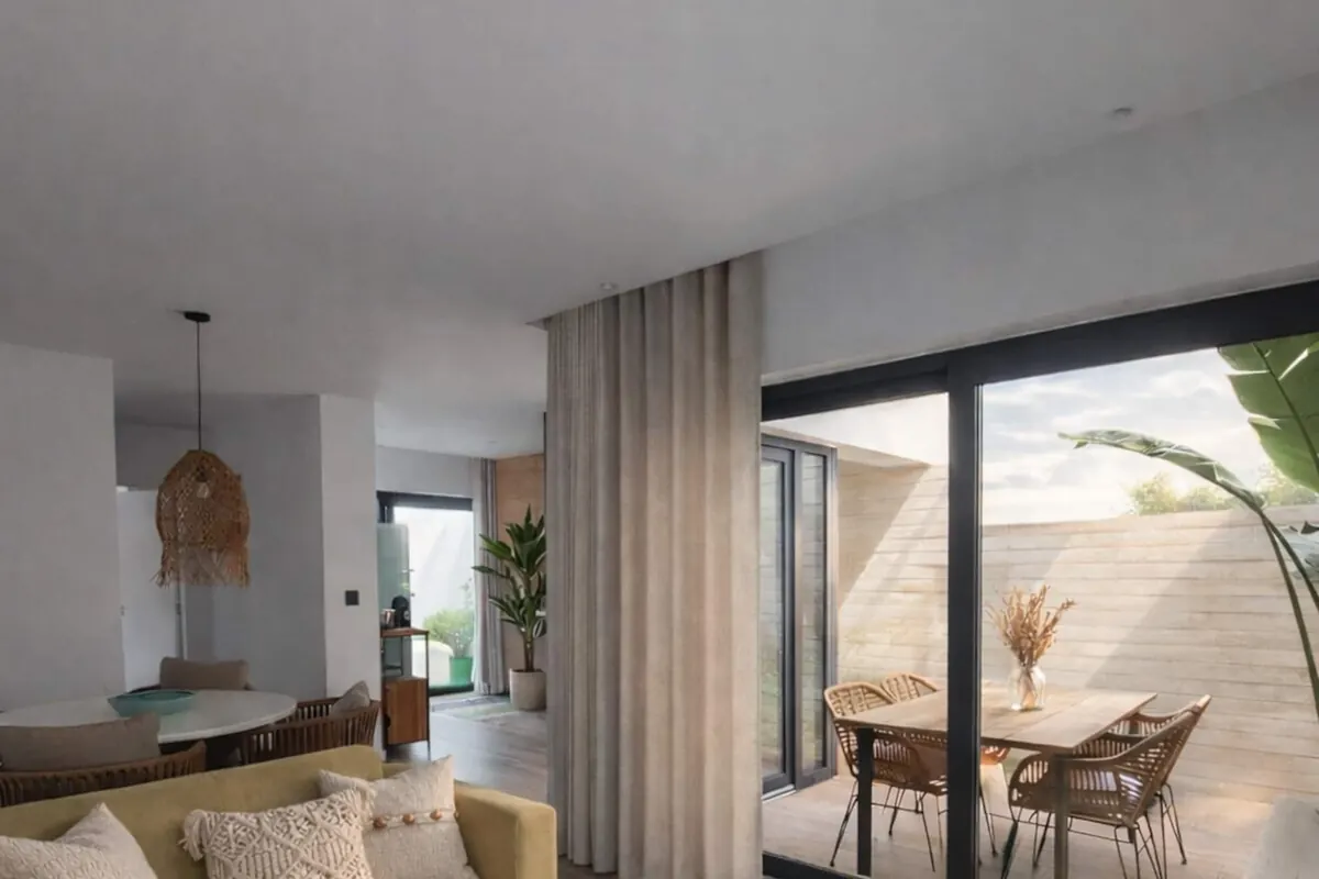 Sala com sofá claro e porta envidraçada aberta para o pátio