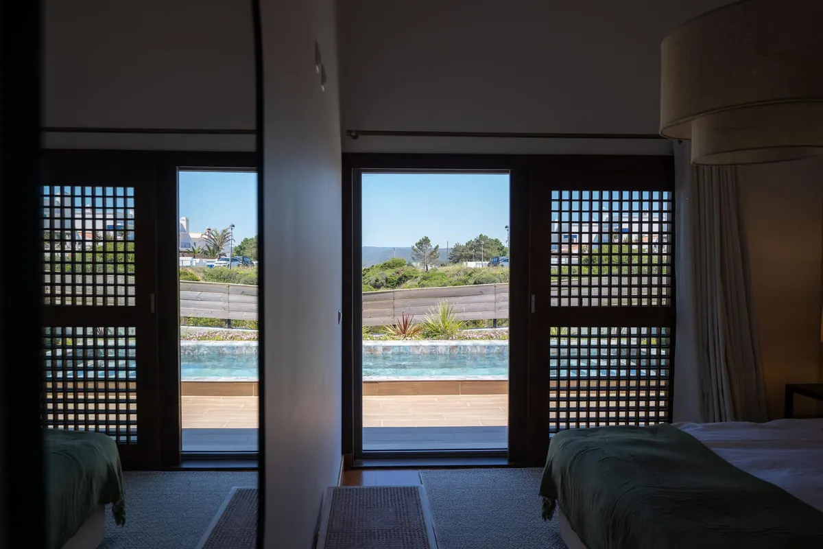 Quarto com portas de correr em treliça de madeira abertas sobre a piscina