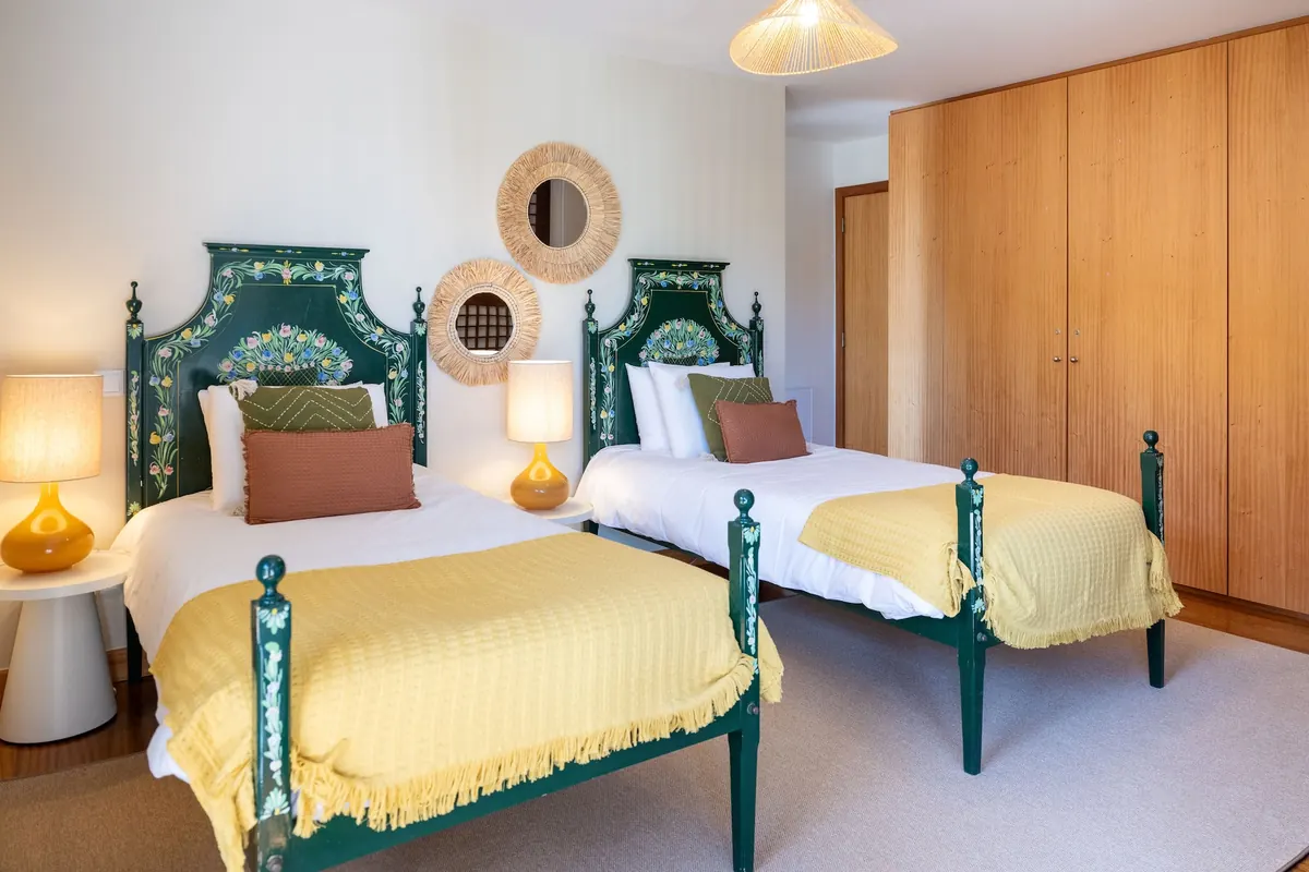 Quarto com duas camas de solteiro e cabeceiras verdes esculpidas