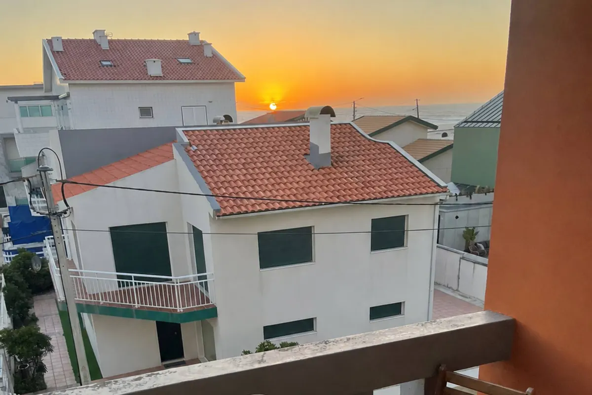 Varanda privada com mesa posta ao pôr do sol, sobre os telhados da Costa Nova