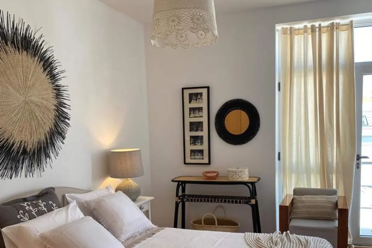 Quarto com cama de casal, espelho circular e luz suave de candeeiro de mesa
