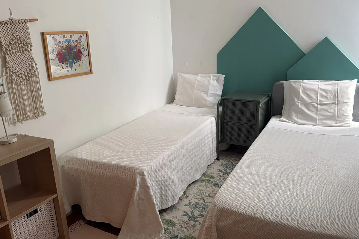 Segundo quarto com duas camas de solteiro e cabeceiras verdes