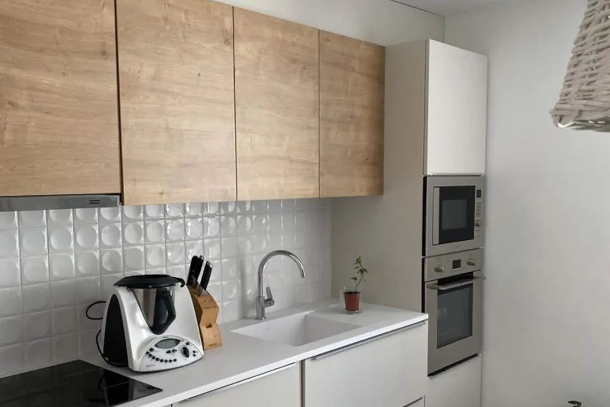 Cozinha equipada em madeira clara e branco, com forno e micro-ondas encastrados