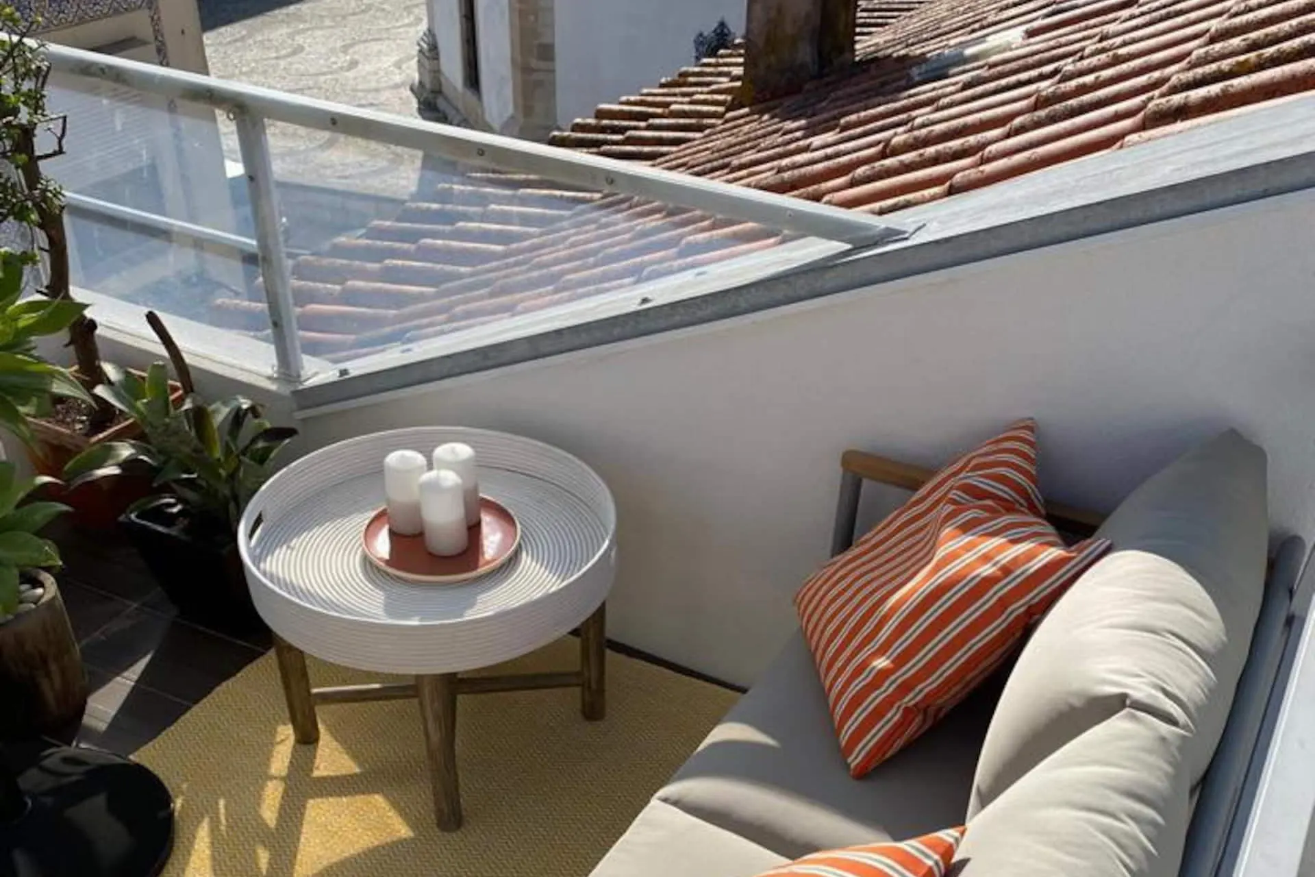 Terraço privado com sofá exterior e almofadas em tons de terracota, sobre os telhados da Beira Mar
